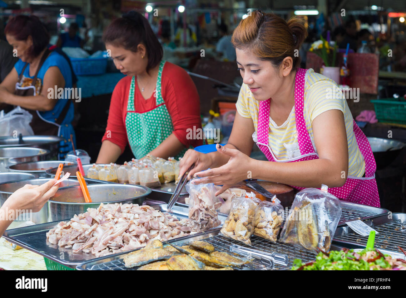 Phitsanulok, Thailand - 1 July 2017 - Female fresh market venders sell their fresh and cooked Thai food to their customers at Sunday morning market in Stock Photo