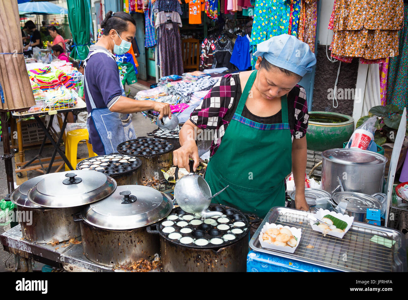 Phitsanulok, Thailand - 1 July 2017 - Street food venders cook their Thai dessert, Kanom Krock, for their customers at Sunday morning market in Phitsa Stock Photo