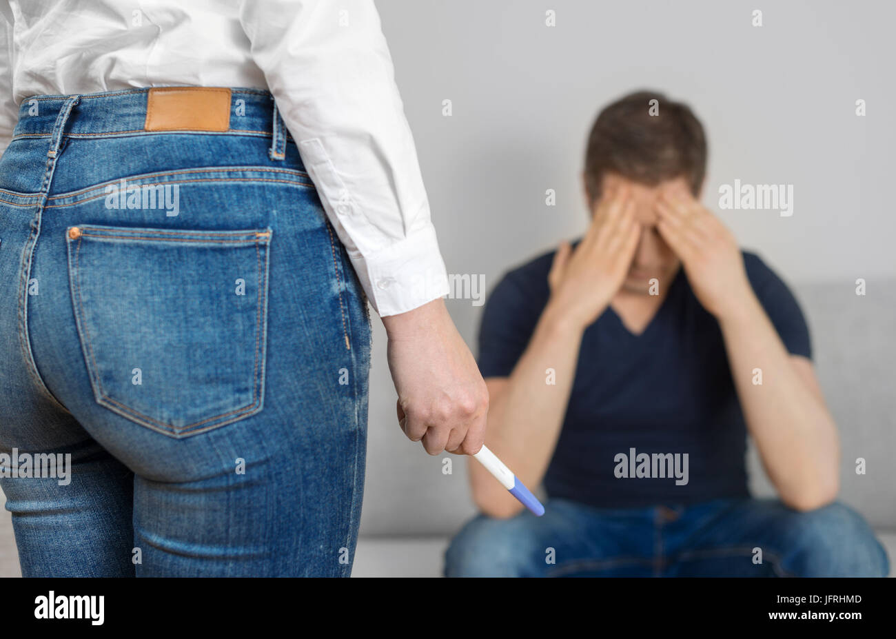 Girl with pregnancy test in front of sad boyfriend. Stock Photo