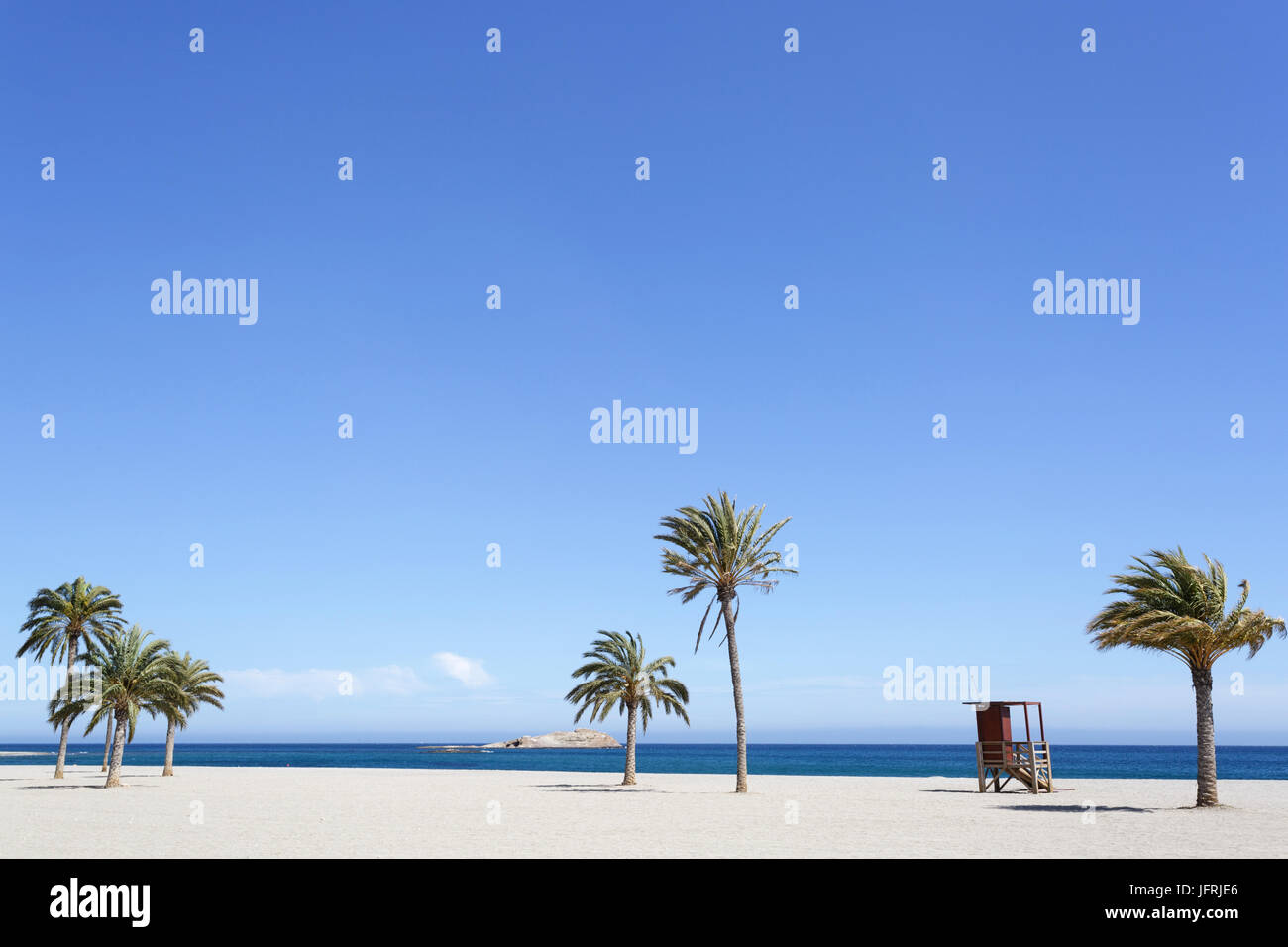 Wooden watchtower between palm trees on the beach of Carboneras, Almeria, Spain. Stock Photo