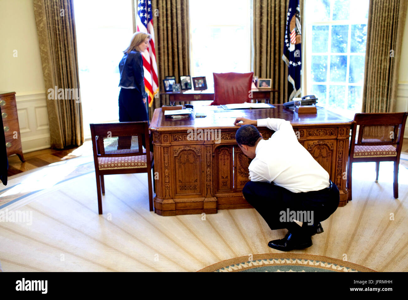 President Barack Obama examines  the Resolute Desk on March 3, 2009, while visiting with Caroline Kennedy Schlossberg in the Oval Office. In a famous photograph, her brother John F. Kennedy Jr., peeked through the FDR panel, while his father President Kennedy worked.  Official White House Photo by Pete Souza Stock Photo
