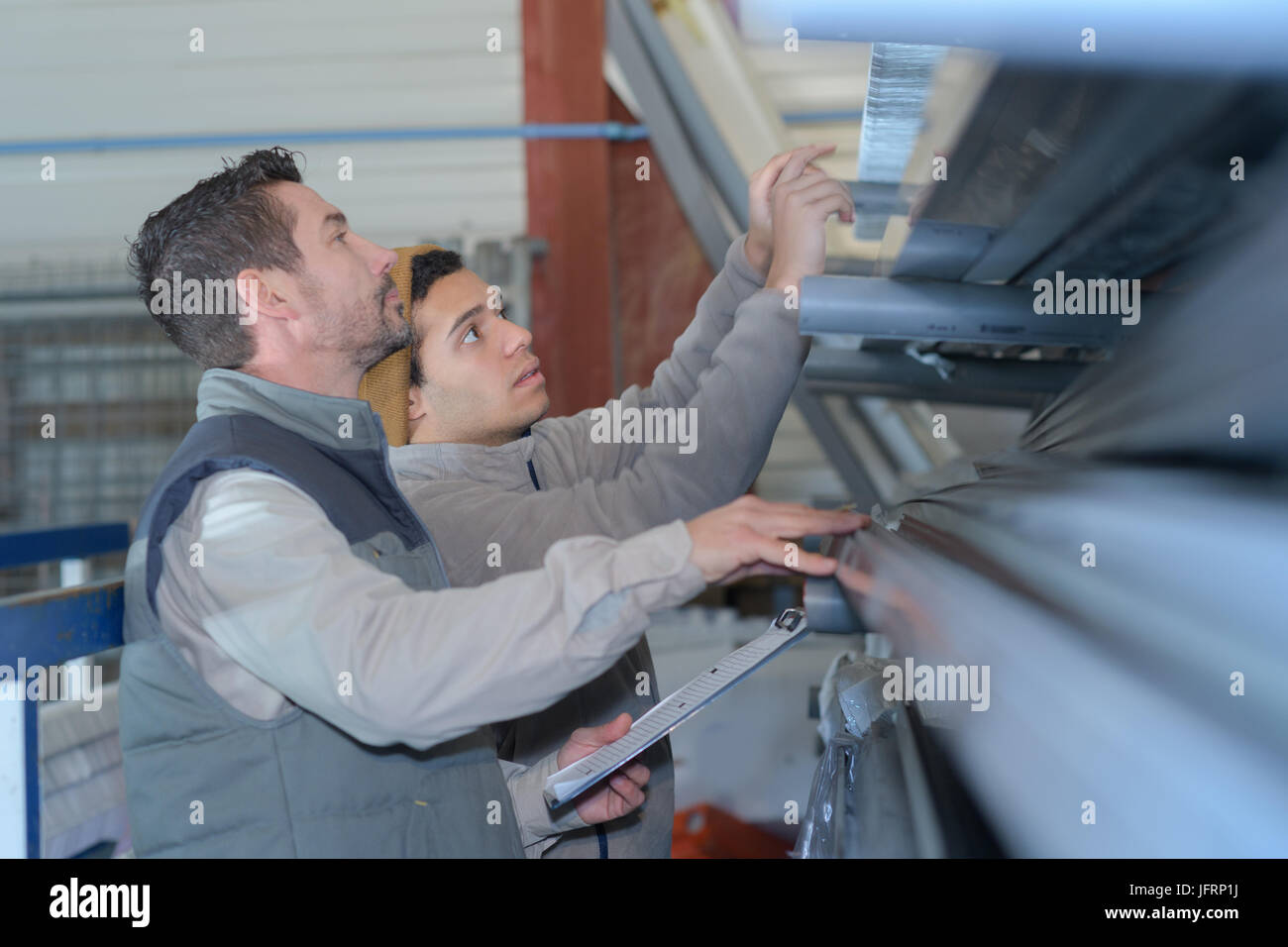 warehouse workers reaching for something in racking storage of goods Stock Photo