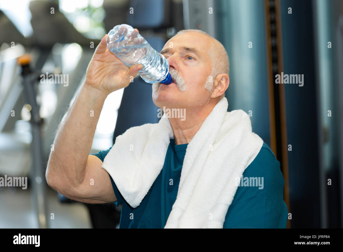 senior man in fitness center drinking from bottle of water Stock Photo ...