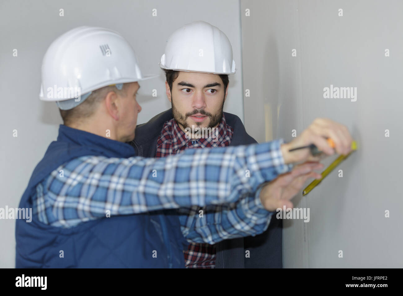 builders measuring wall with tape measure Stock Photo