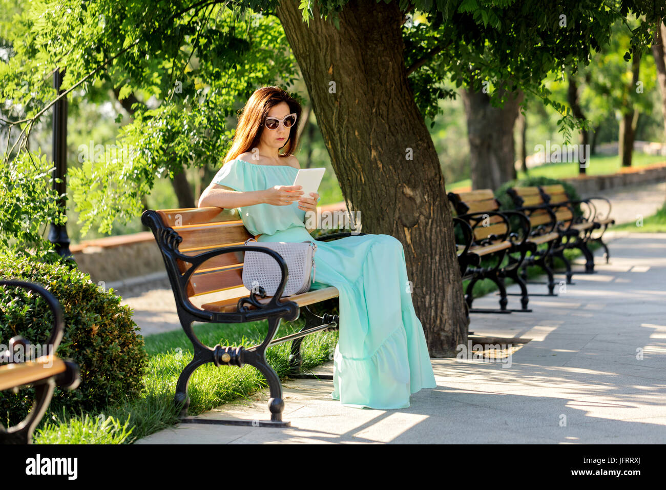 Young beautiful woman in a light green pastel long dress is sitting on ...