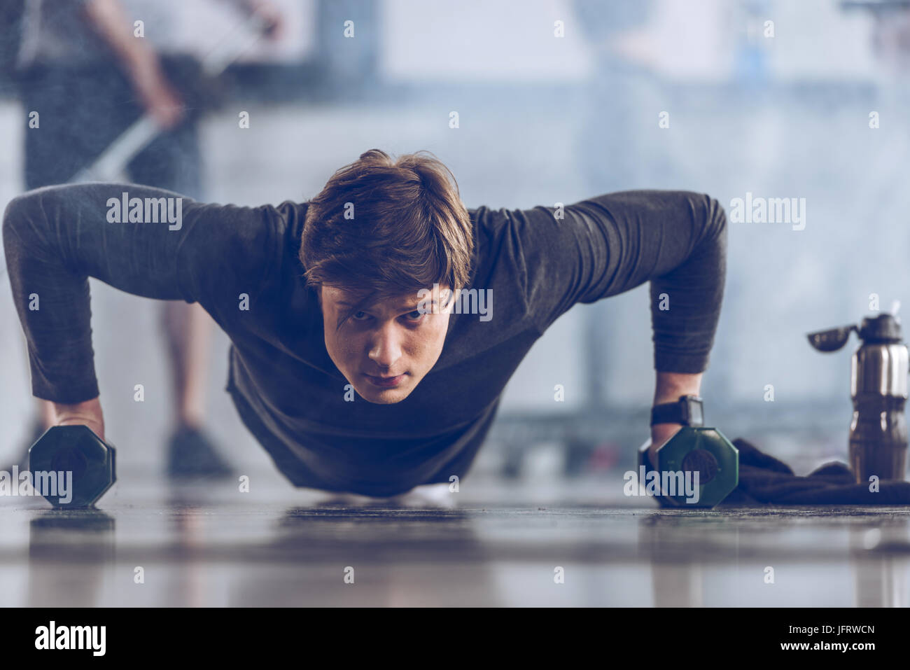 athletic young sportsman doing push ups with dumbbells at the gym, gym ...