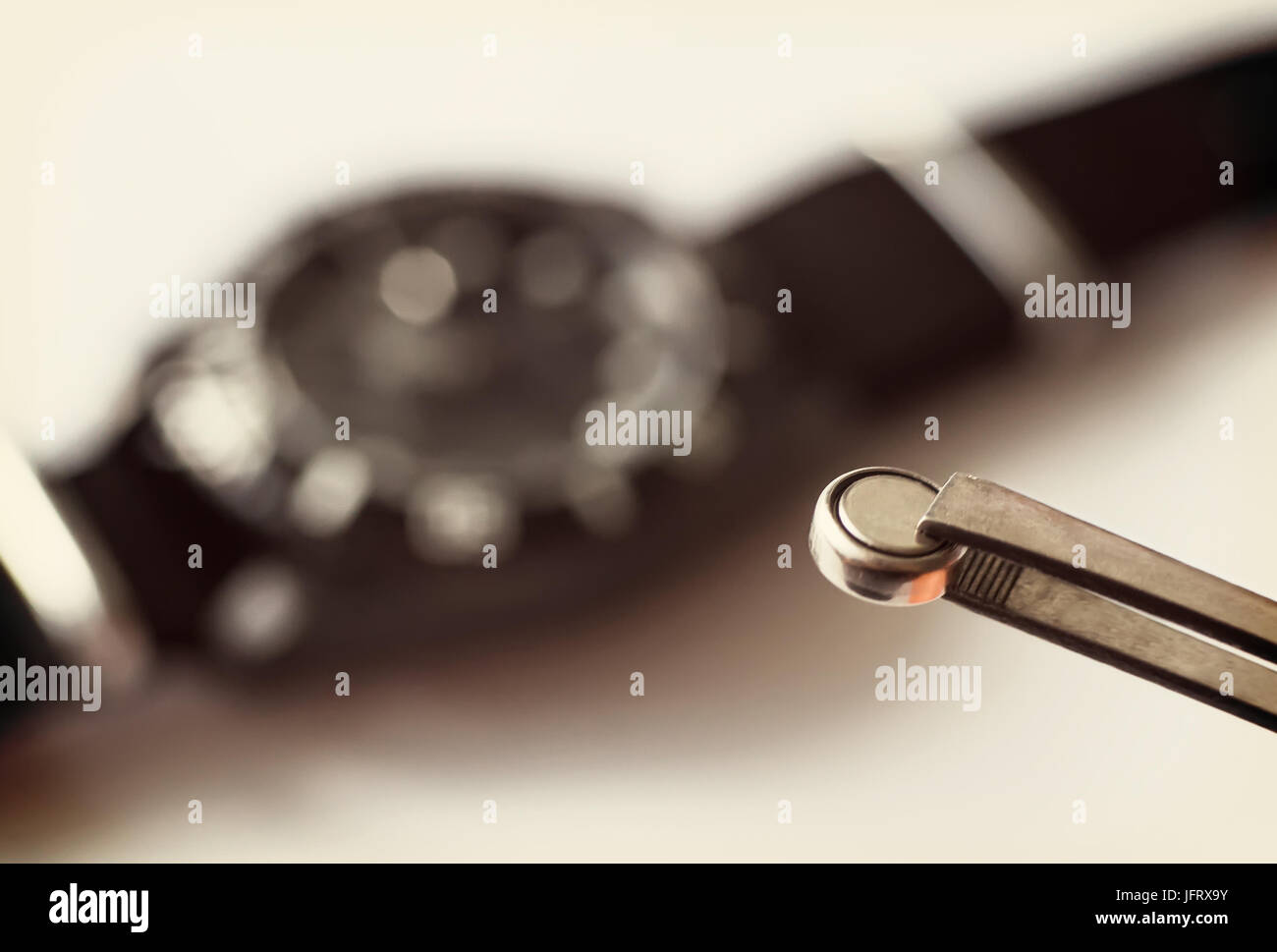 Replace the battery in a wristwatch. Closeup Of Tweezers Placing