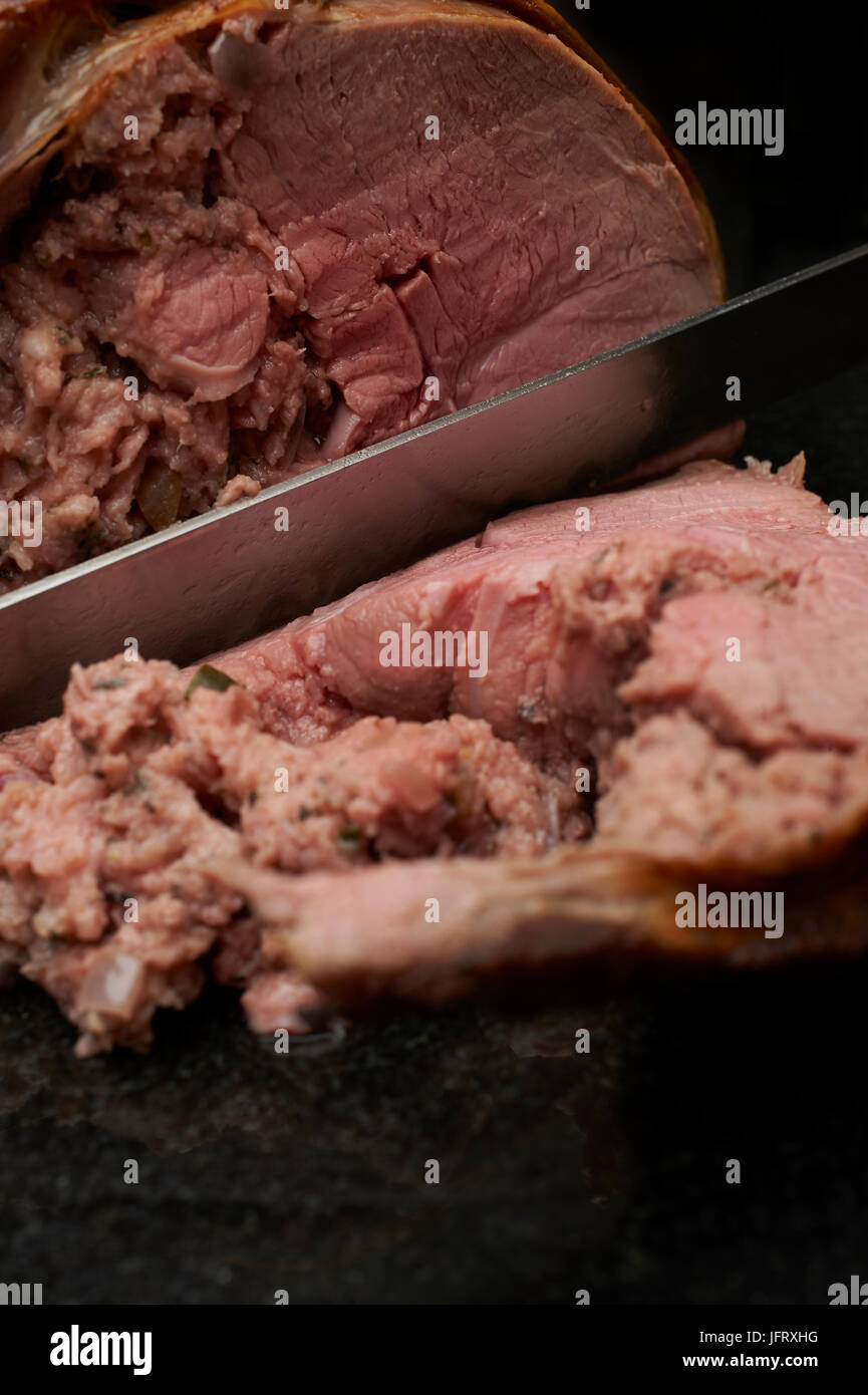 Carving a roast leg of english lamb with stuffing in the centre of the