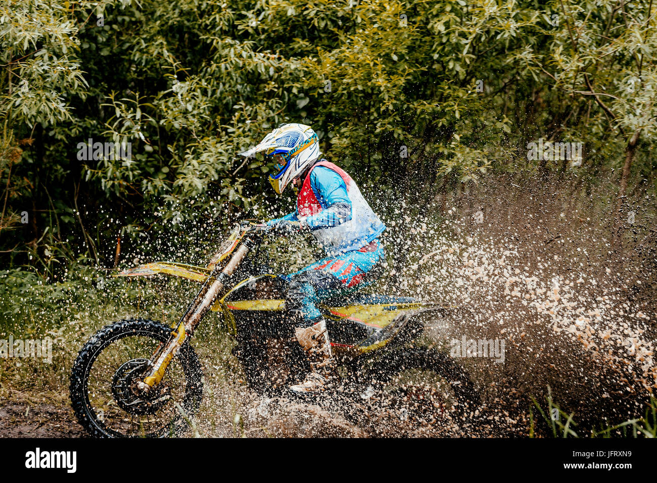 motorcycle rider crosses puddle splashes of water and dirt during Ural Cup in Enduro Stock Photo