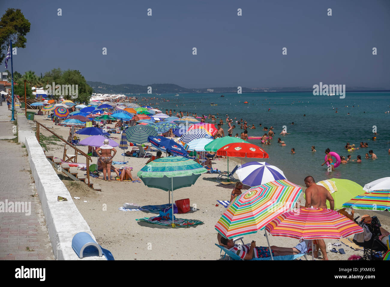 Sunbathers on a beach with beach umbrellas at Chalkidiki peninsula. Stock Photo