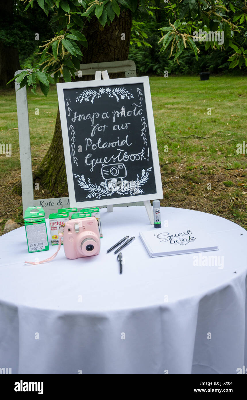 A table at a wedding reception with a guest book and an instant camera. Stock Photo