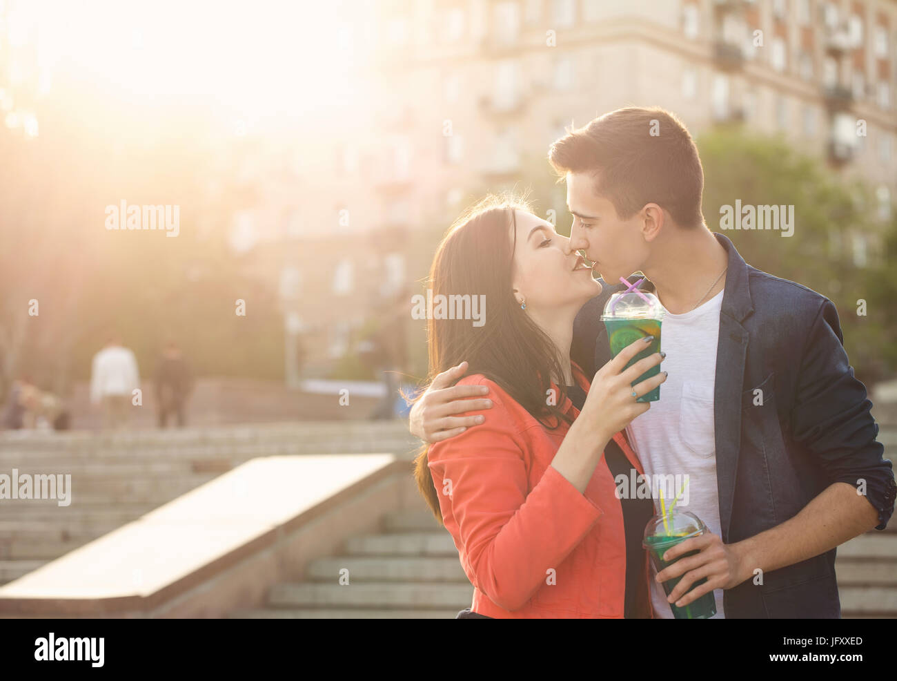 Teenagers drink fruit fresh from glasses. They are kissing. A couple in love on a date. Romance of first love. Stock Photo