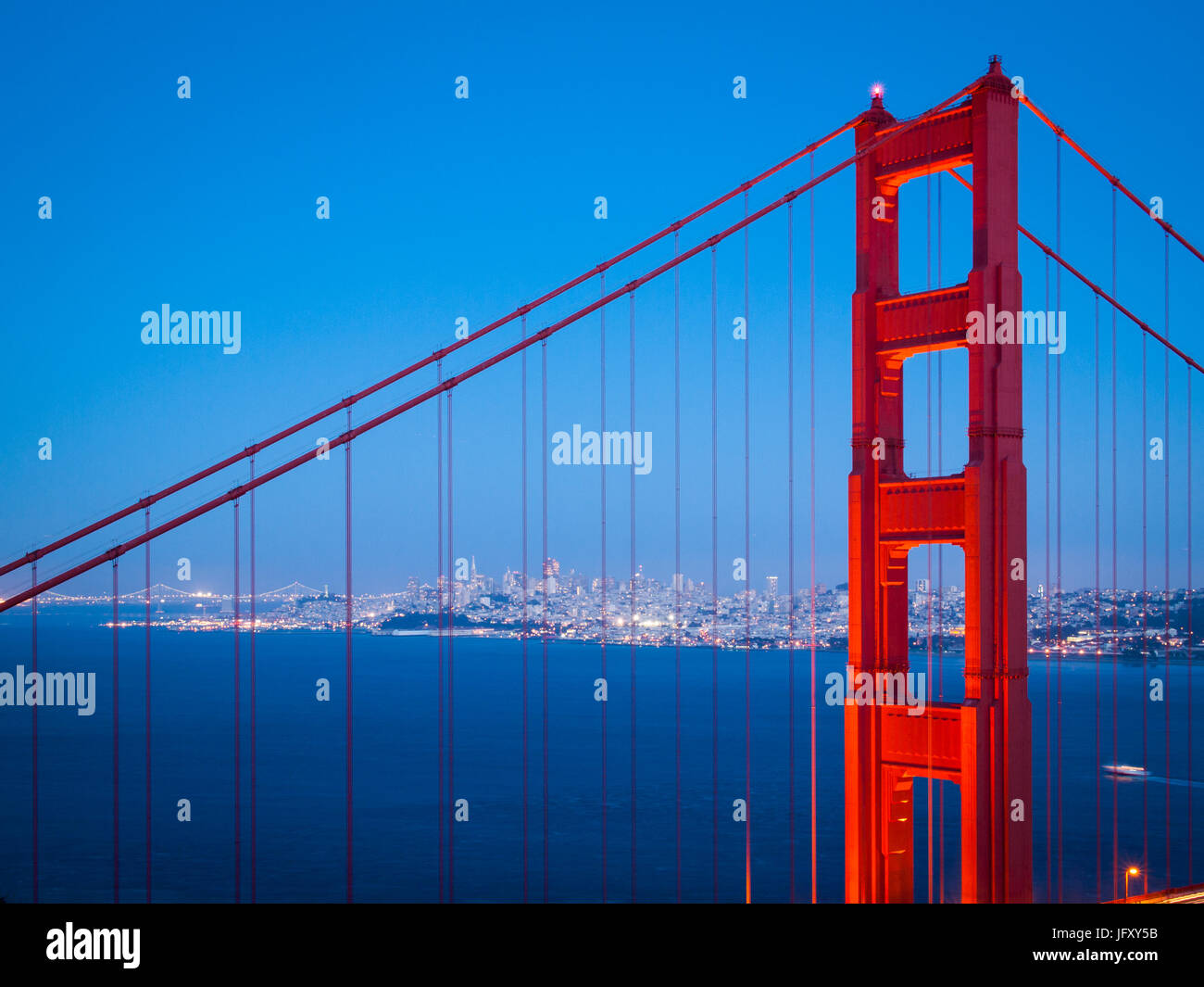 A spectacular view of the Golden Gate Bridge at night, with the illuminated skyline of San Francisco in the background Stock Photo