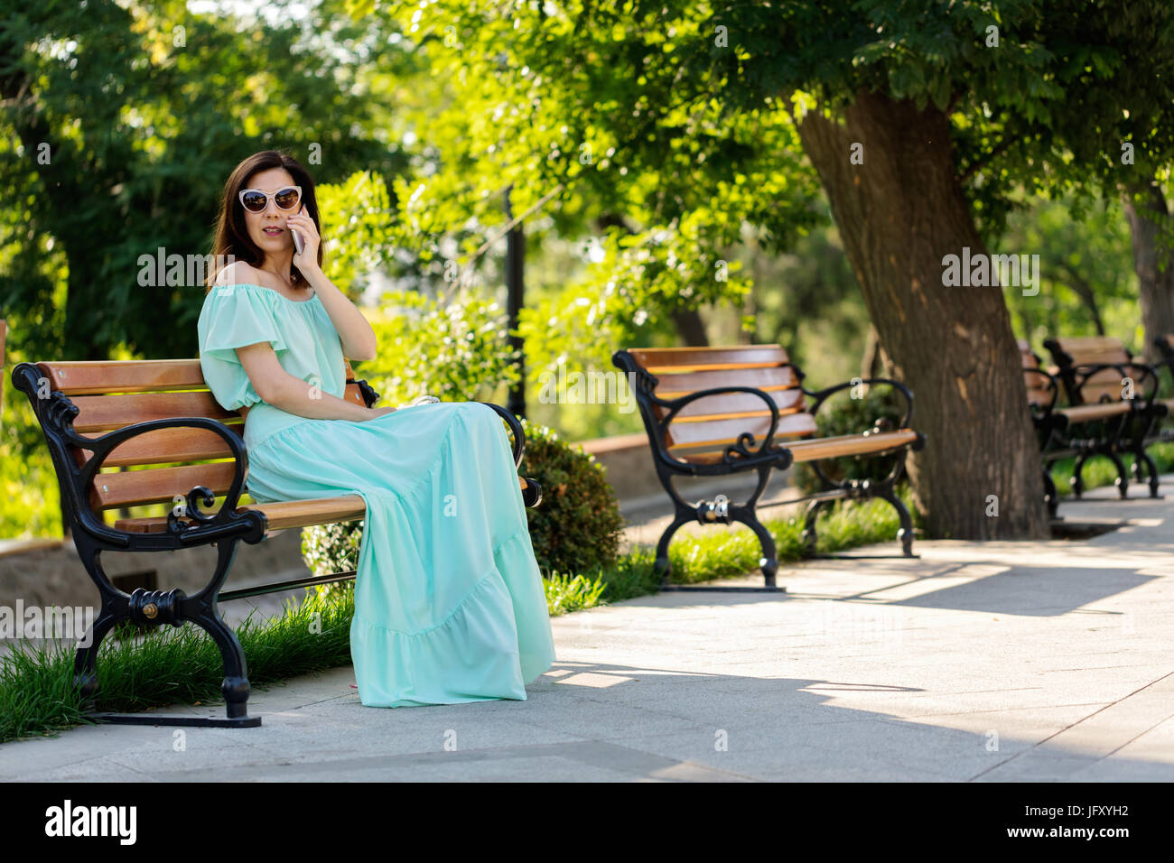 Young beautiful woman in a light green pastel long dress is sitting on ...