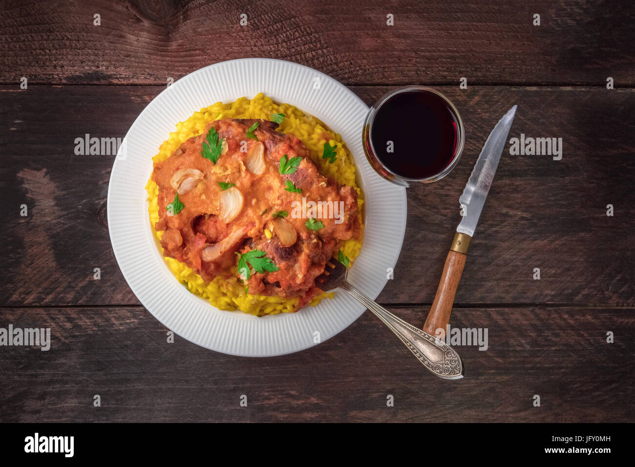 Photo of ossobuco, traditional Italian dish, served with risotto alla milanese, saffron rice