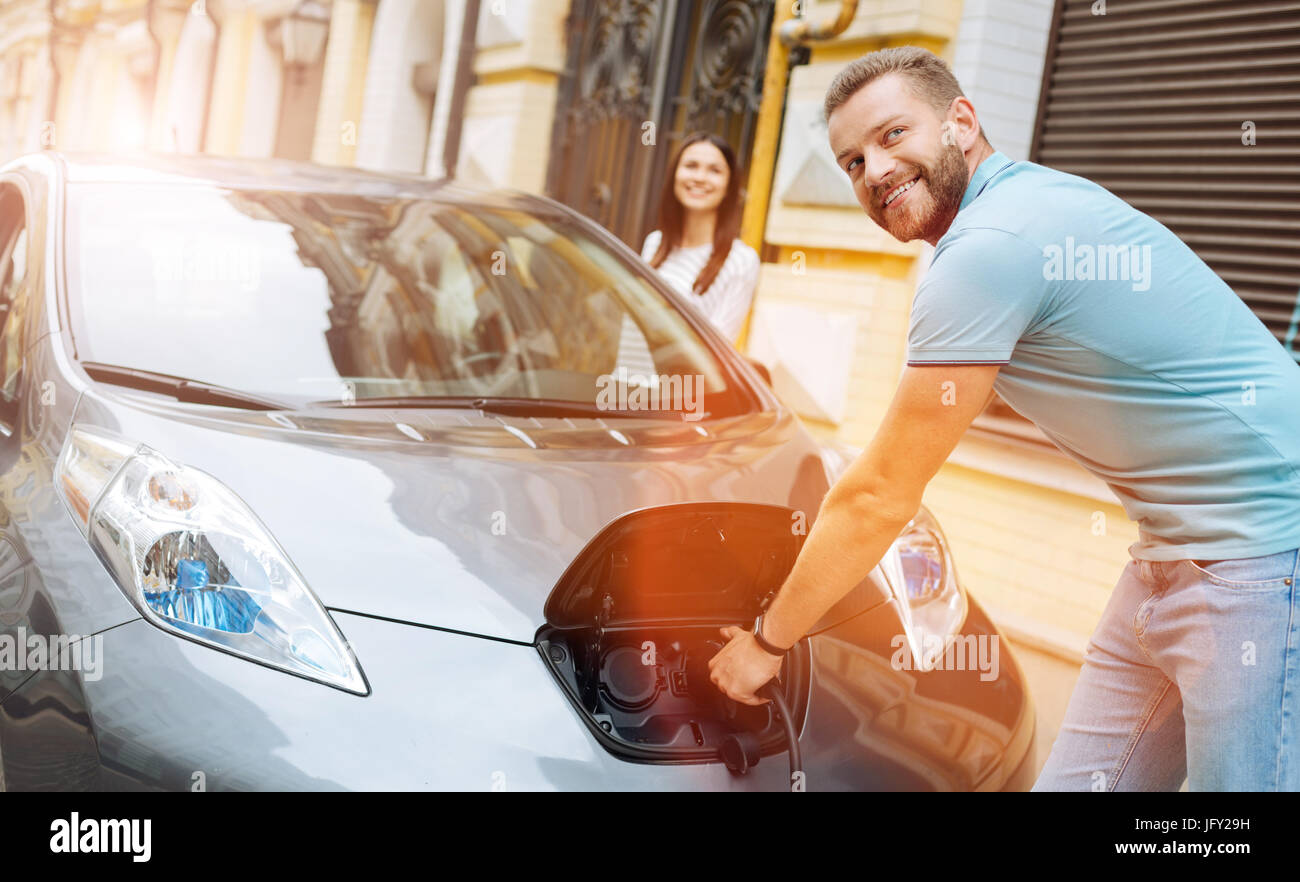 Smiling man unplugging the charger from the car Stock Photo