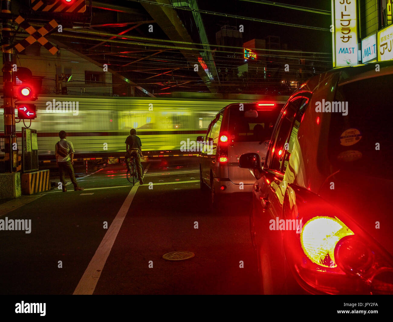 Stop light. Cars and people waiting for train to pass through road crossing, night street, Kawagoe, Saitama, Japan Stock Photo