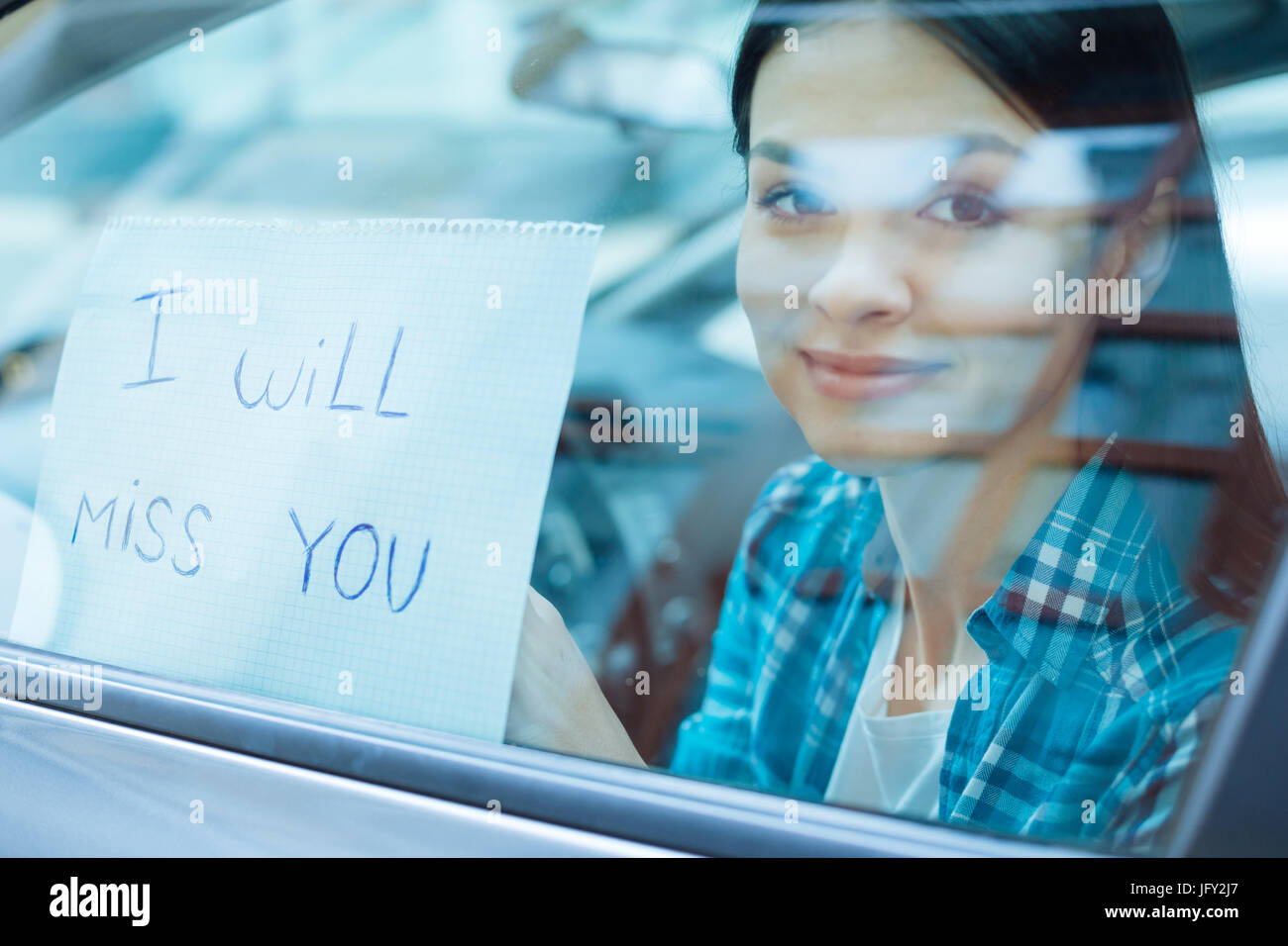 Beautiful woman pressing a farewell note to car window Stock Photo