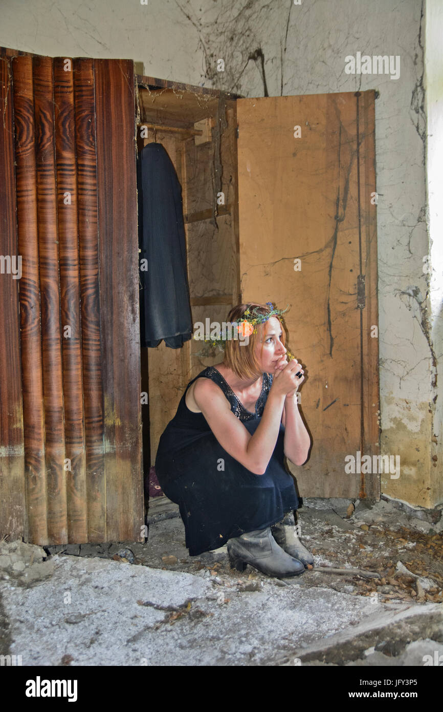 Sad girl is sitting in the closet and thinking about past times. Stock Photo