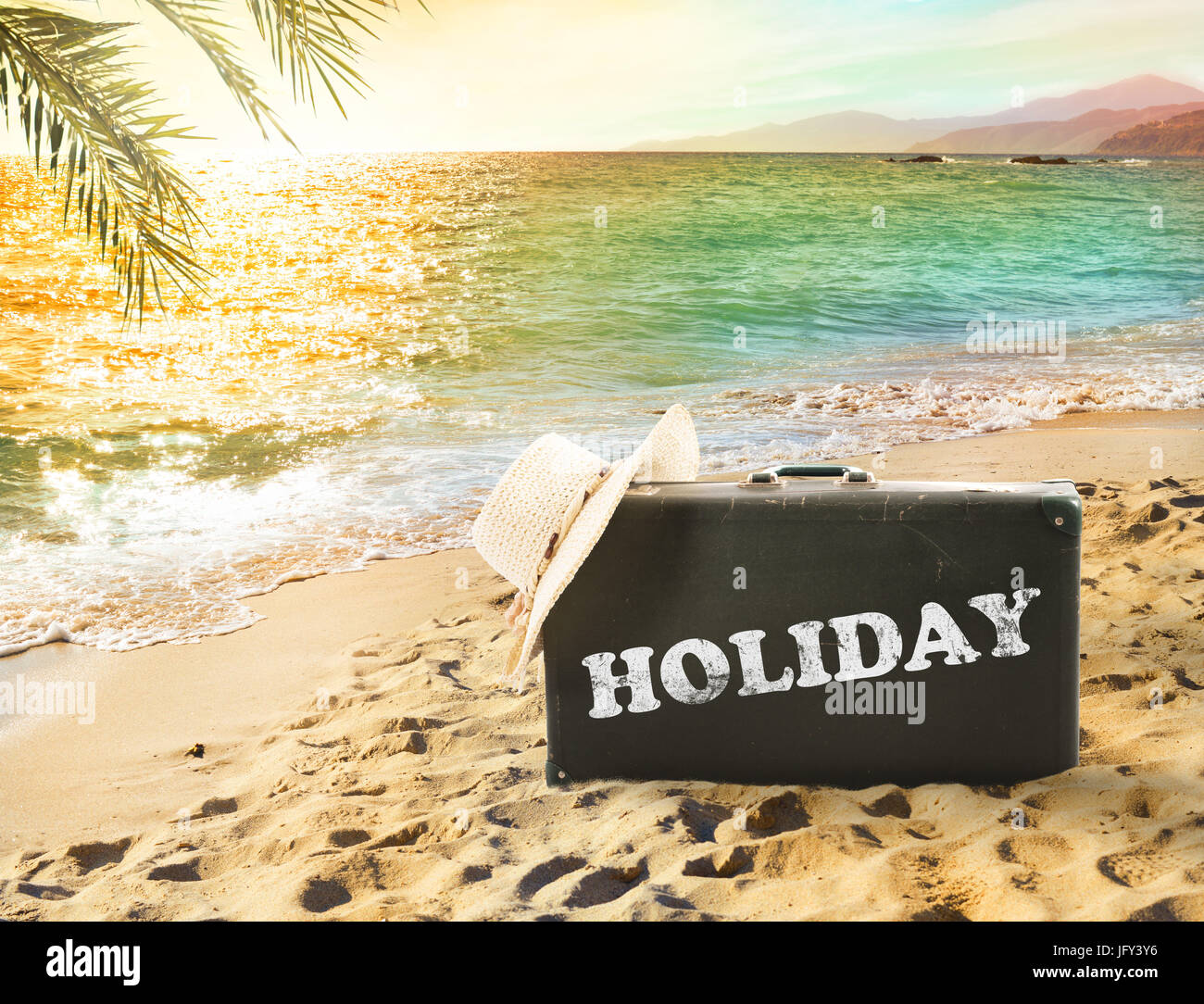 Suitcase in a tropical beach with holiday writing Stock Photo