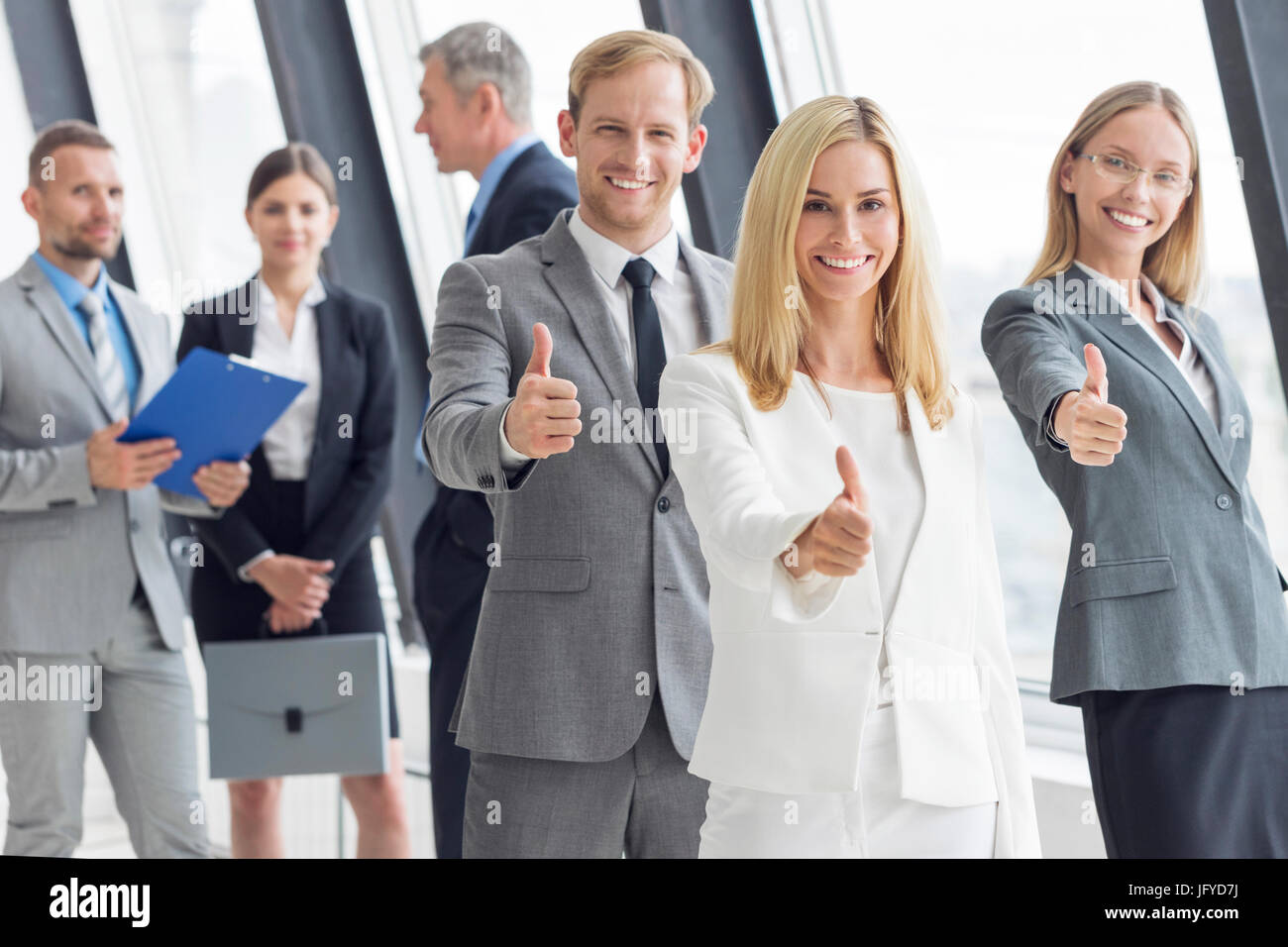 Successful young business people showing thumbs up sign Stock Photo - Alamy