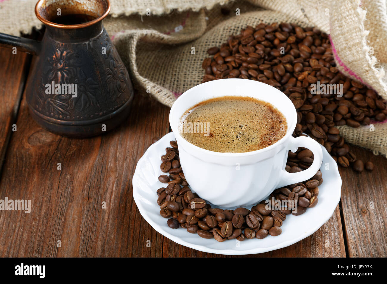 Cup with coffee on the table next to coffee beans Stock Photo