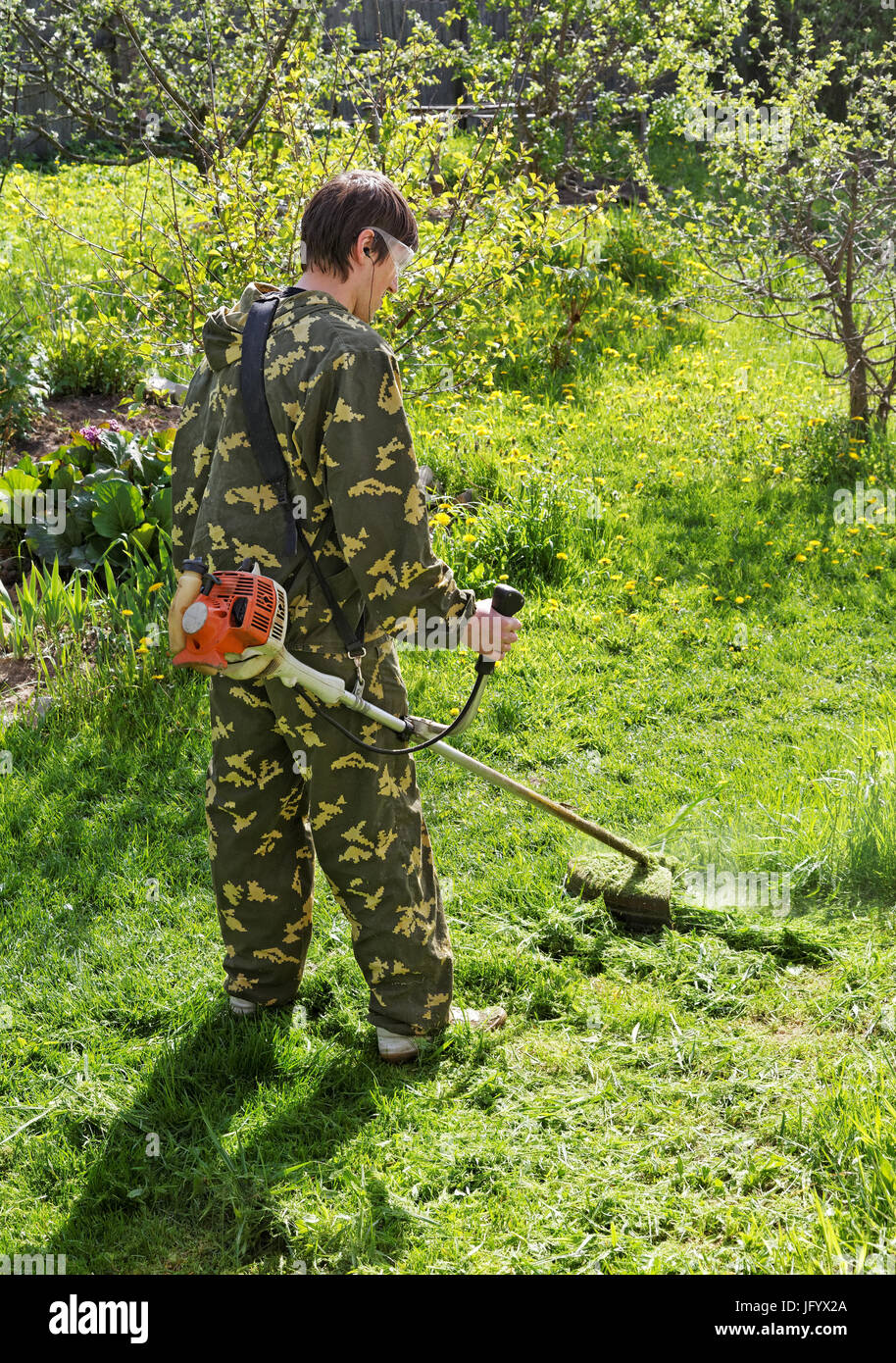 Man mows the grass in his garden summer day Stock Photo