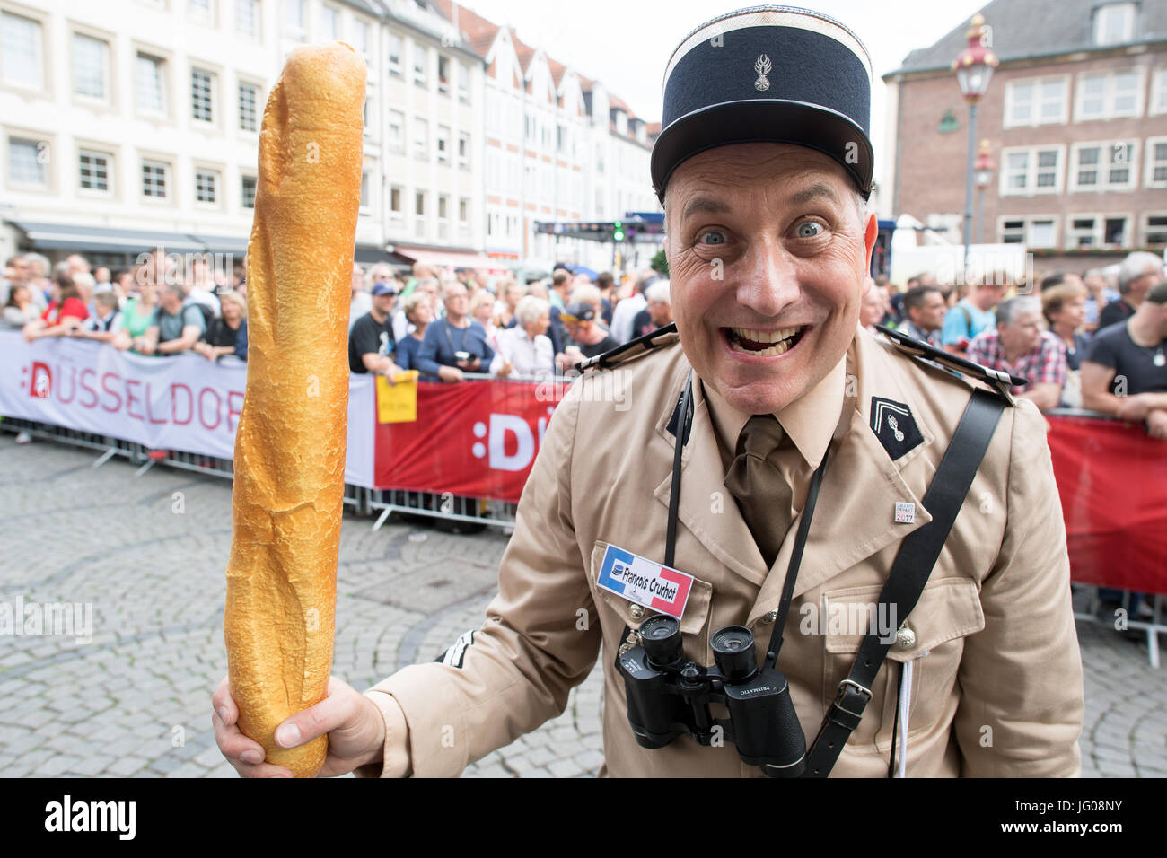 An actor dressed as the 'Gendarm Francois Cruchot' holds a baguette during the Tour de France team presentations in Duesseldorf, Germany, 29 June 2017. Photo: Federico Gambarini/dpa Stock Photo