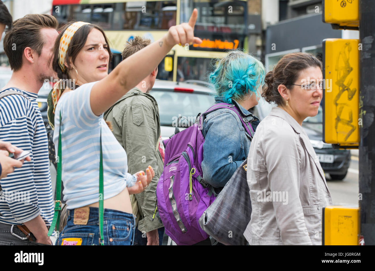 People waiting at traffic lights to cross a busy road in a city. Stock Photo