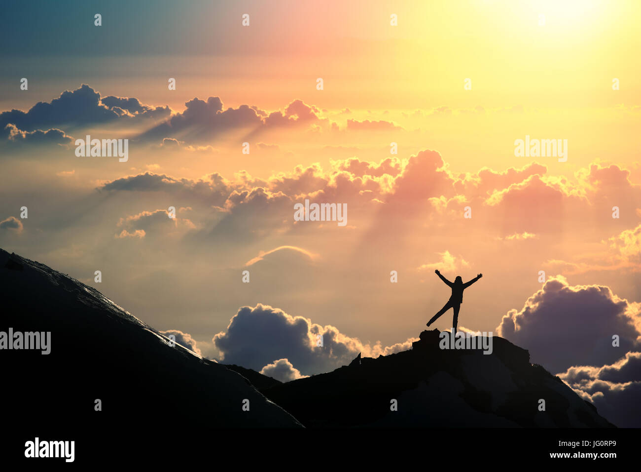 A person is standing on the top of the mountain above the clouds. Stock Photo