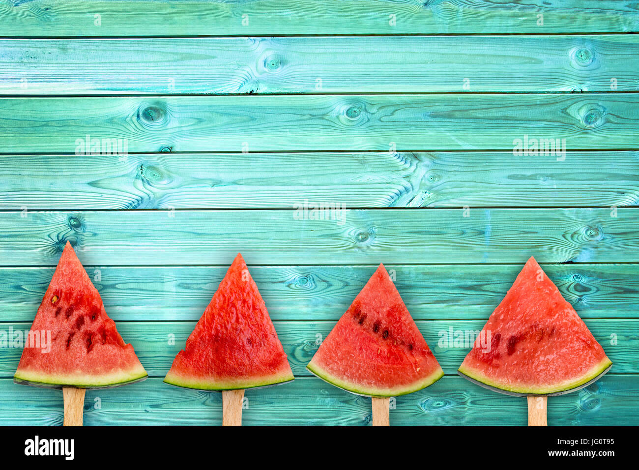 Four watermelon slice popsicles on blue wood background with copy space, fresh summer fruit concept Stock Photo