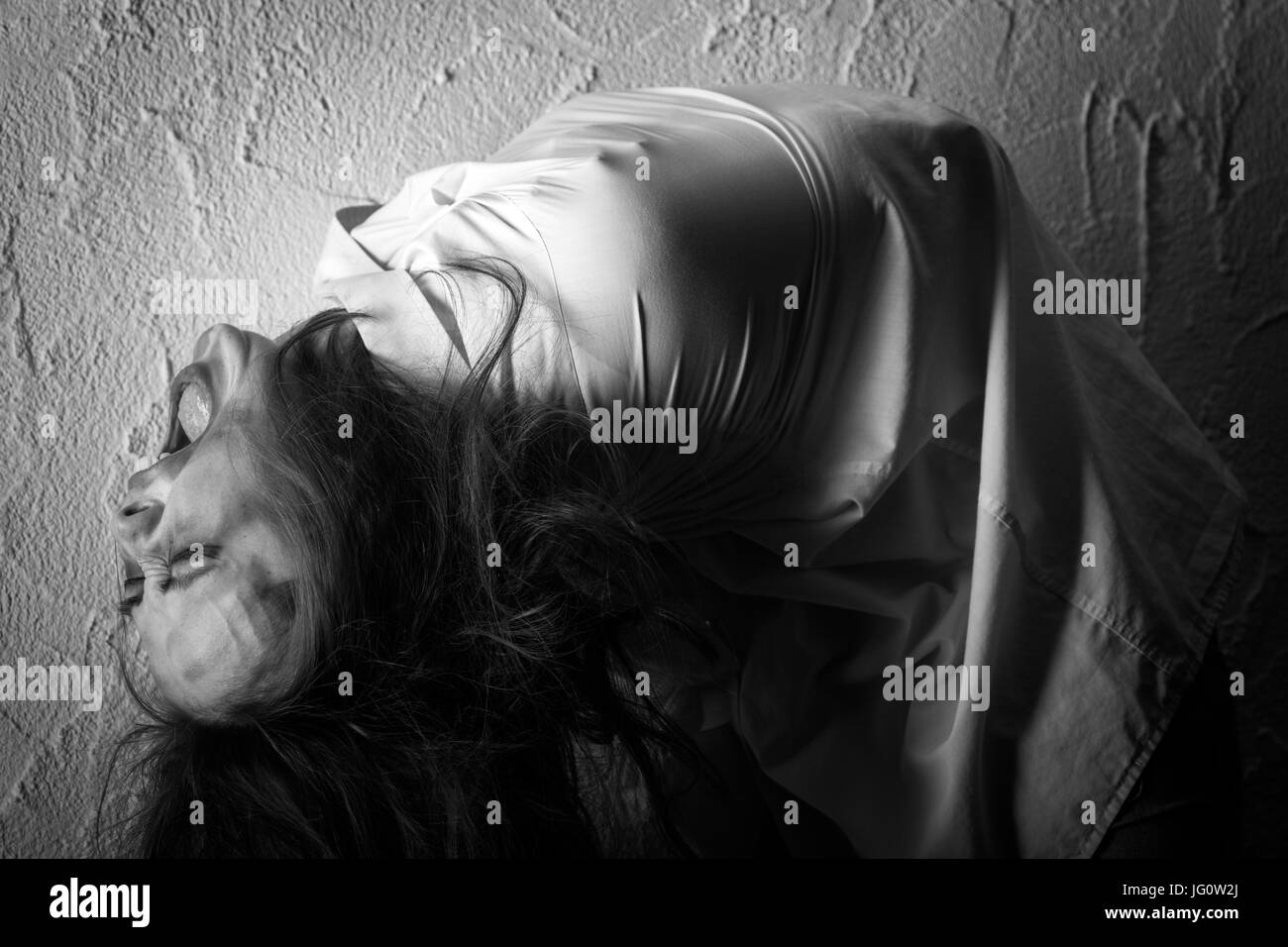 screaming crazy woman with flying hair in straitjacket, monochrome Stock Photo