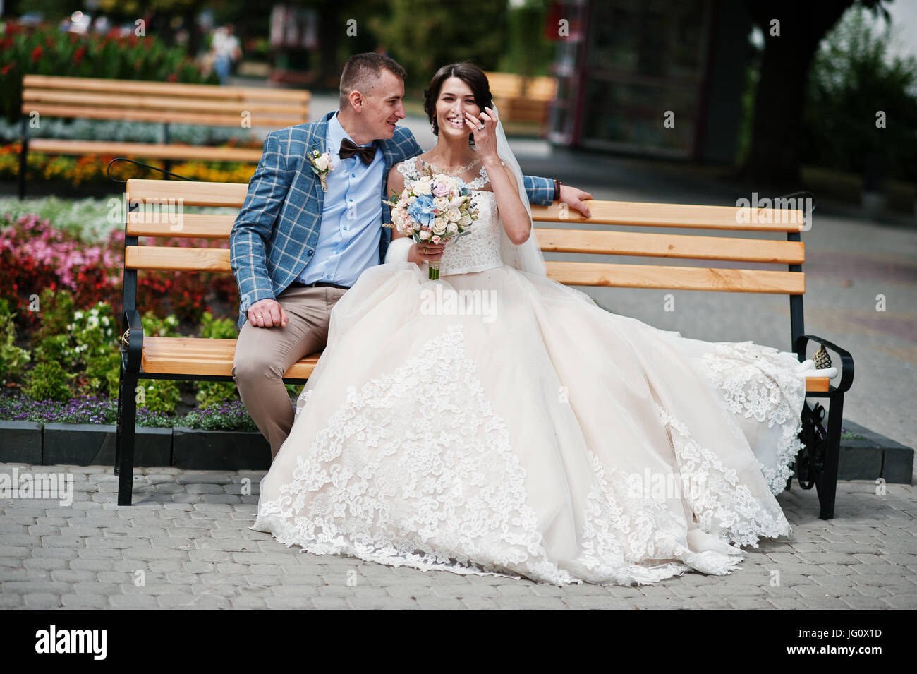 Beautiful wedding couple sitting on a bench in the city centre on a ...
