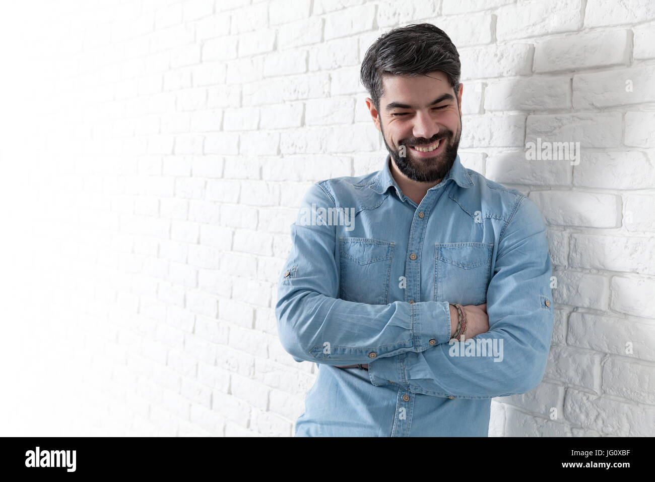 Handsome man leaning against a white brick wall Stock Photo - Alamy