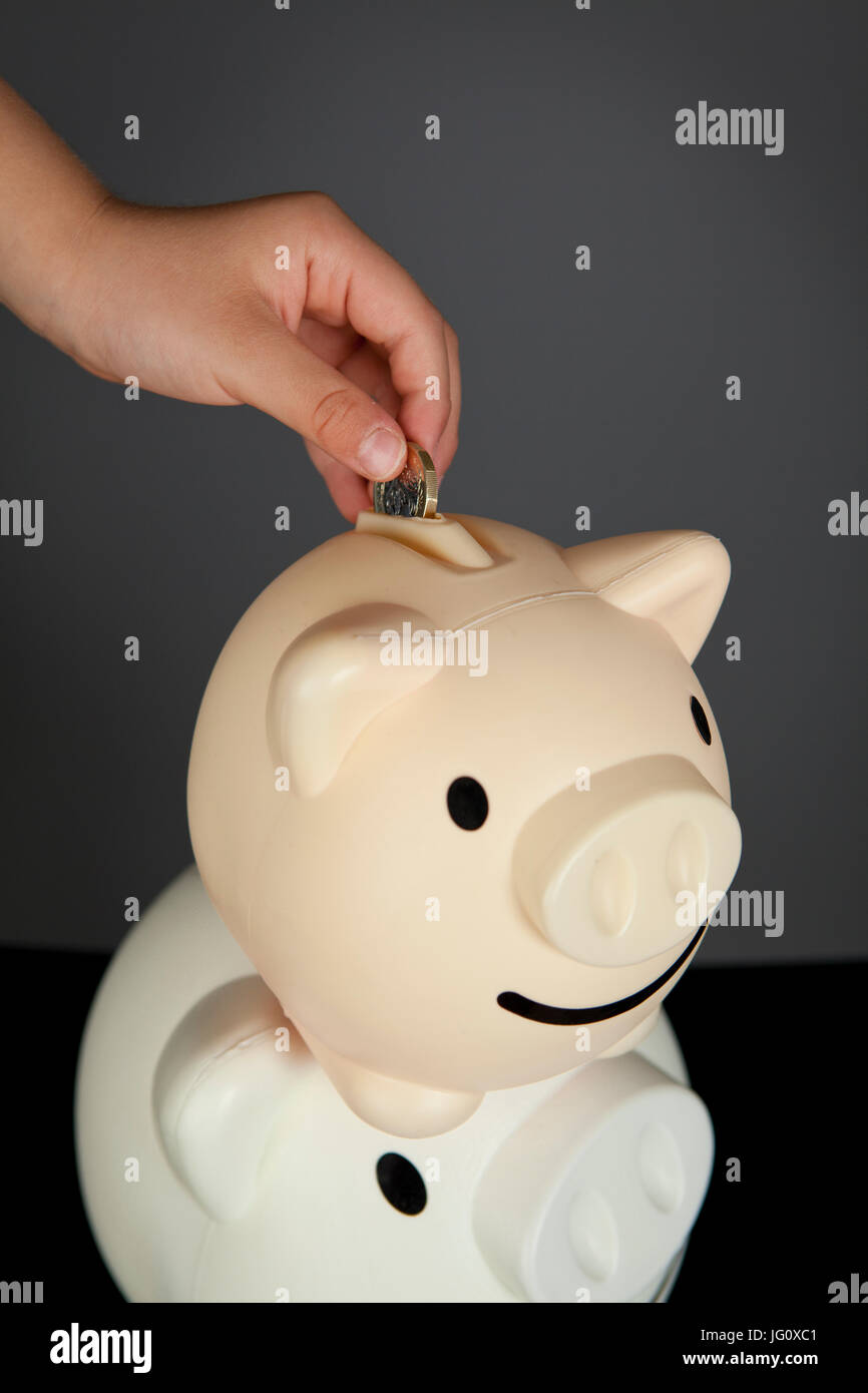Children putting coins in a piggy bank hi-res stock photography and ...