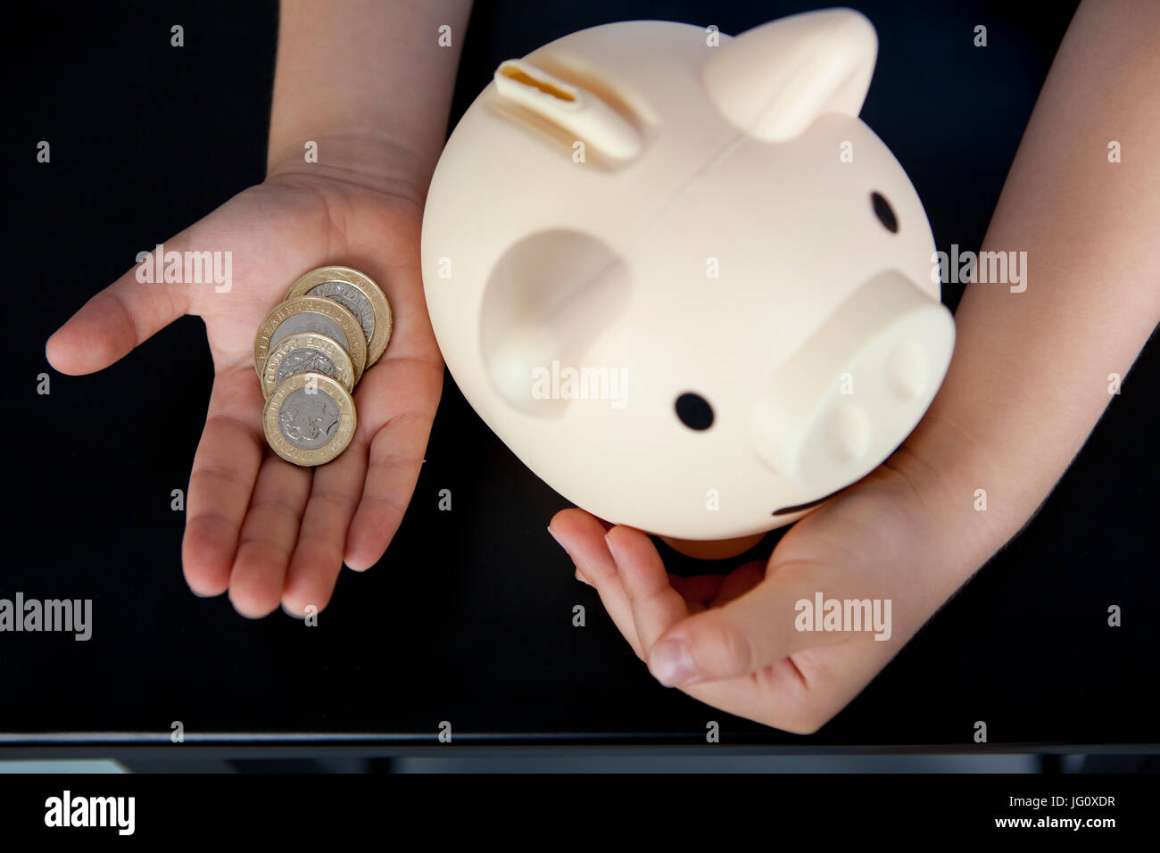 a boy in school uniform putting money in his piggy bank Stock Photo - Alamy
