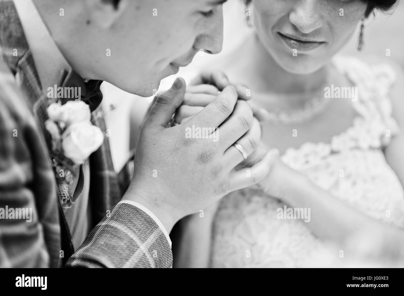Young gorgeous wedding couple sitting by the glass table with a bouquet. Black and white photo. Stock Photo