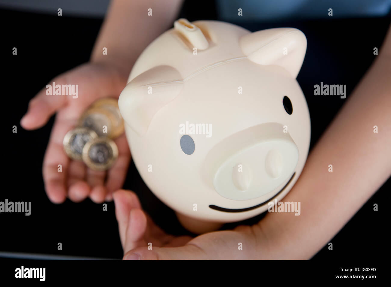 a boy in school uniform putting money in his piggy bank Stock Photo - Alamy