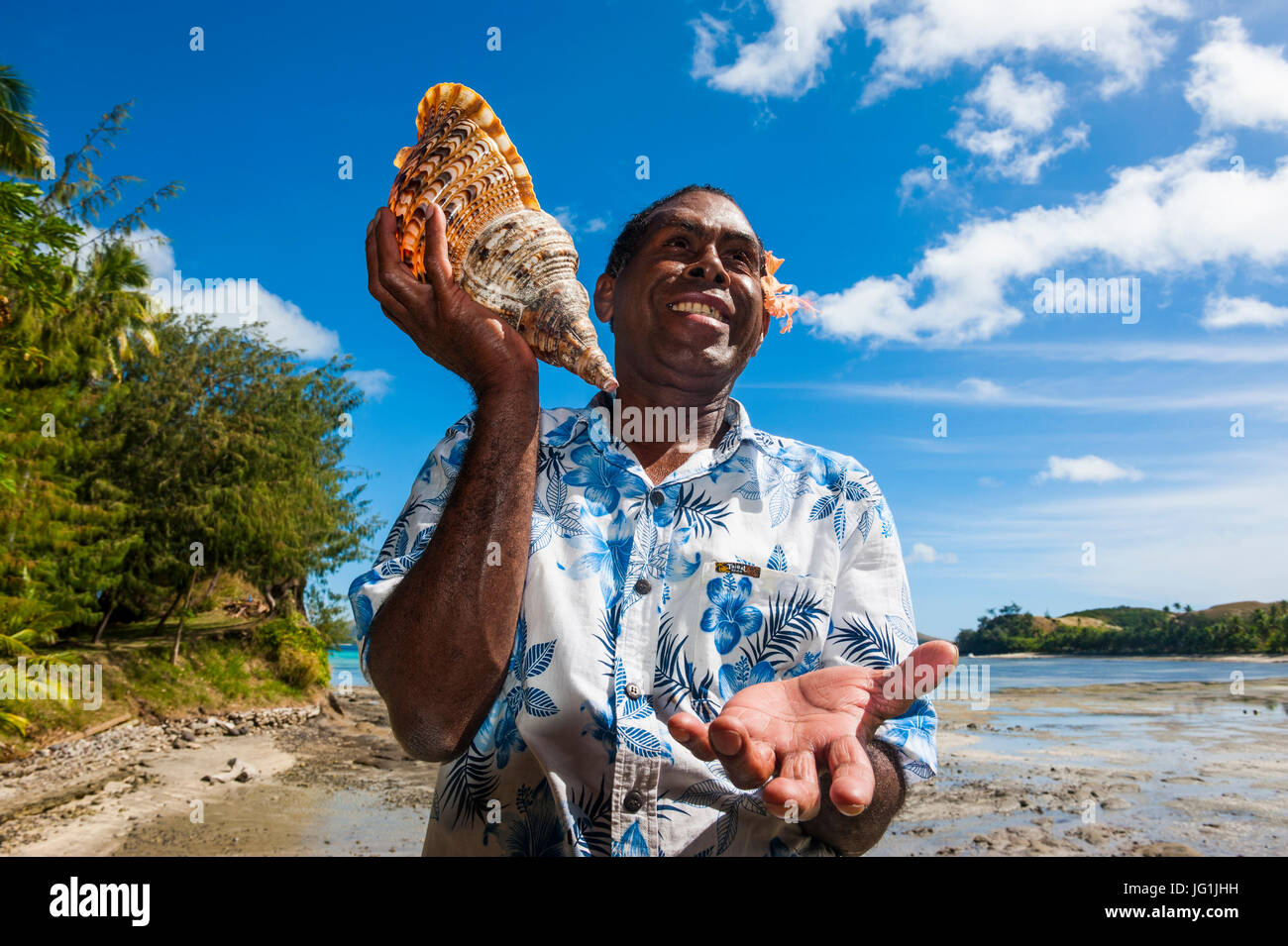 Local fijian man blowing on a huge shell, Safe Landing resort, Nacula island, Yasawas, Fiji, South Pacific Stock Photo