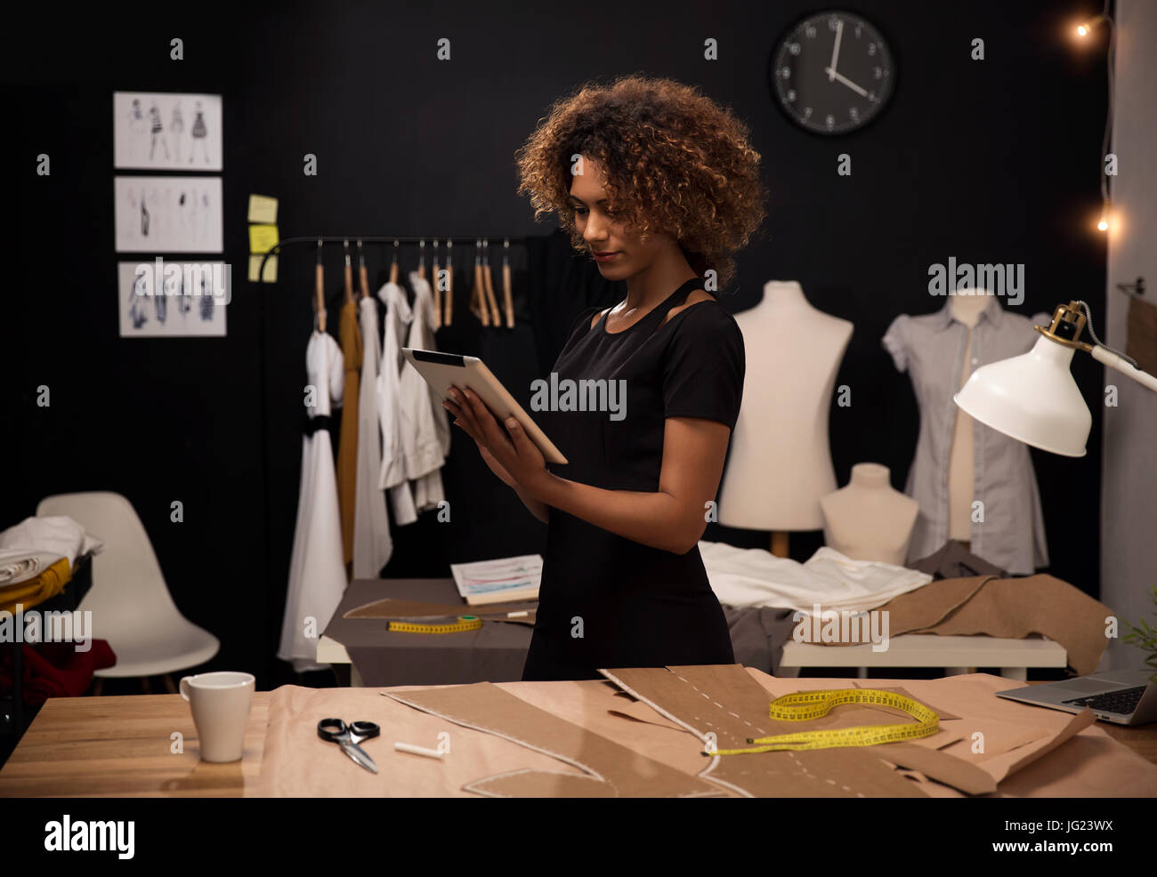 A young fashion designer on her atelier working with a tablet Stock ...