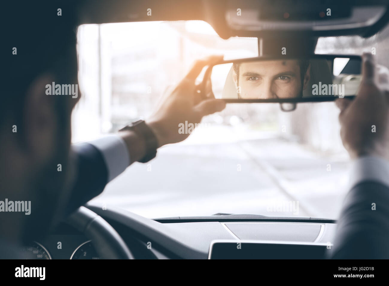 Young business person test drive new vehicle straighten mirror Stock Photo