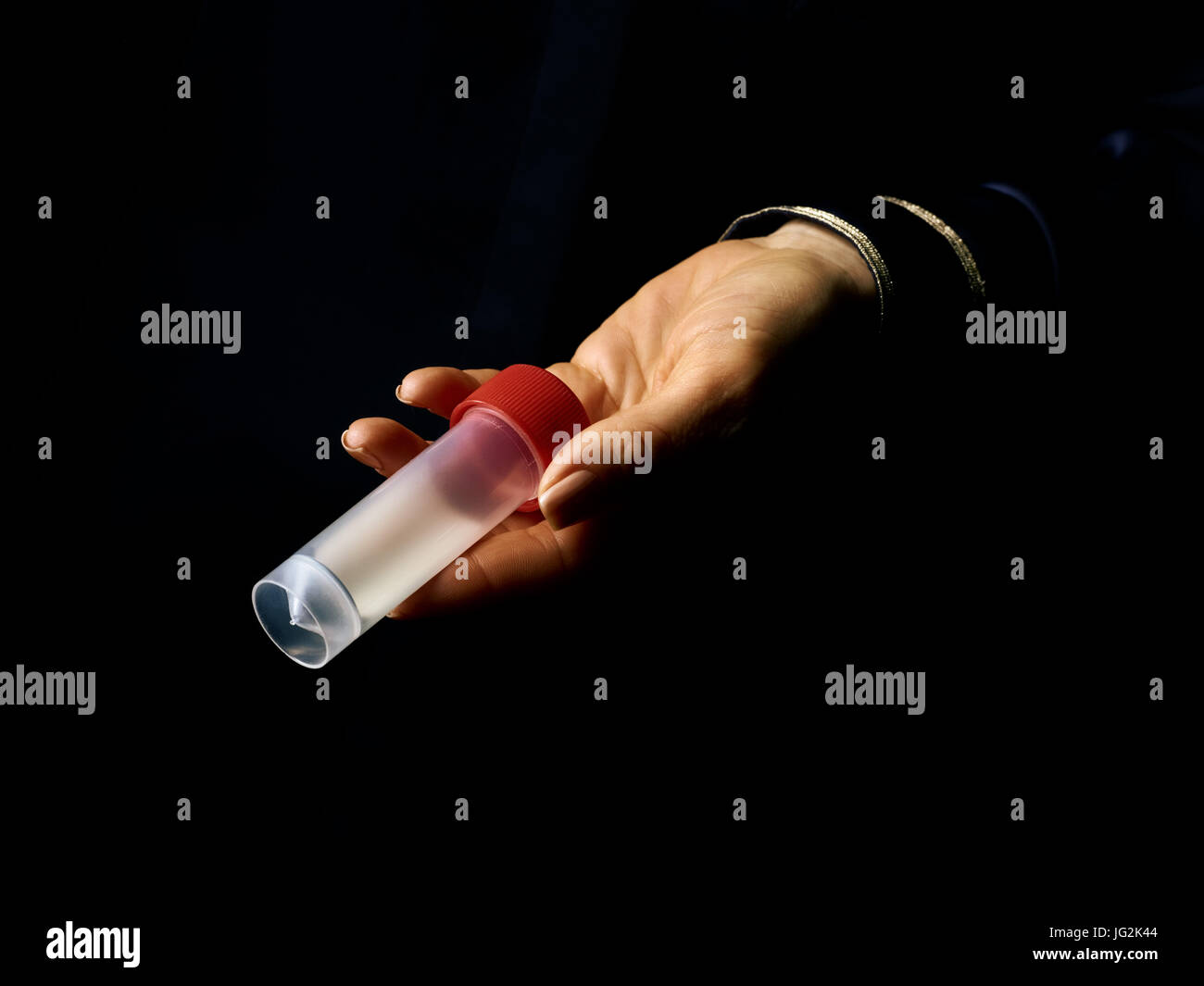 Black Mania. woman hand isolated on black showing sample jar Stock Photo
