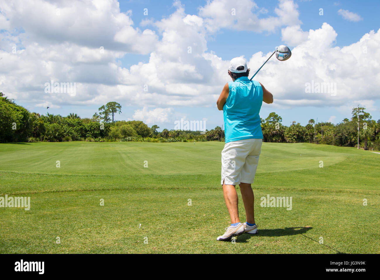 Golfer Hitting Ball on Beautiful Golf Course Stock Photo