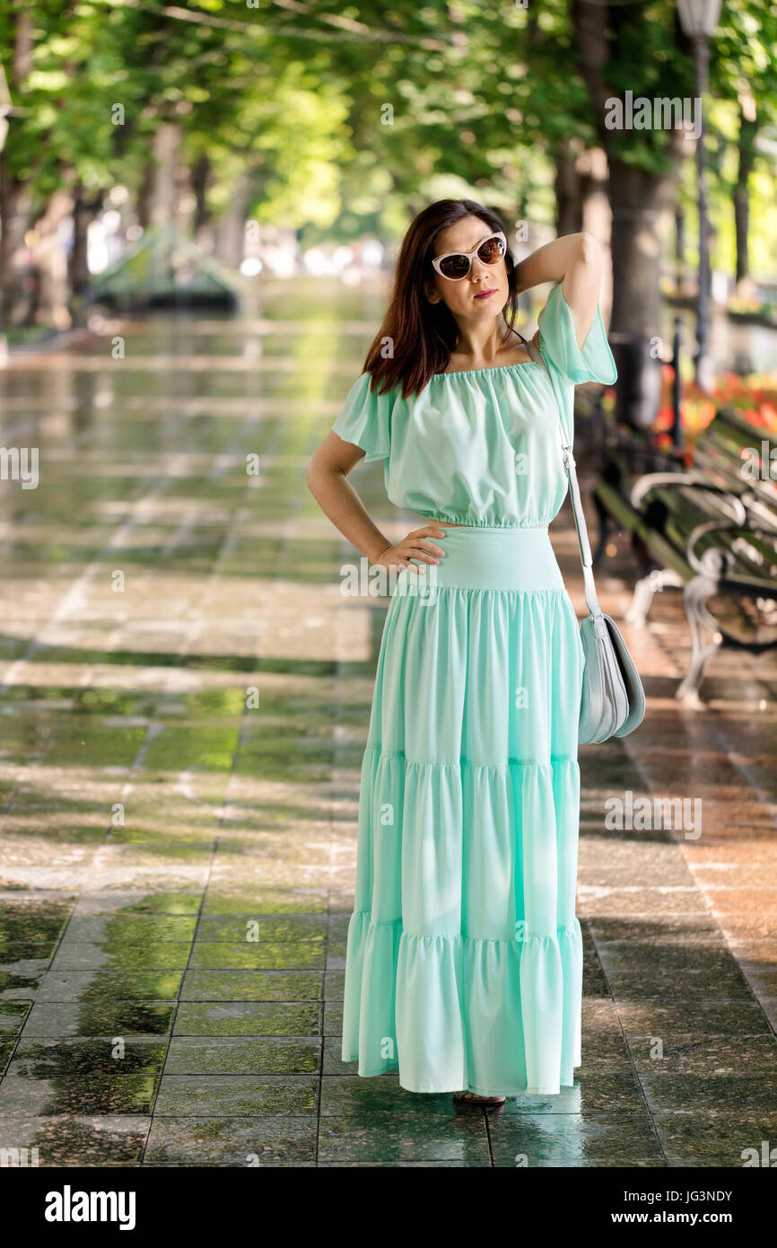 Young beautiful woman in a light green pastel long dress is walking in ...