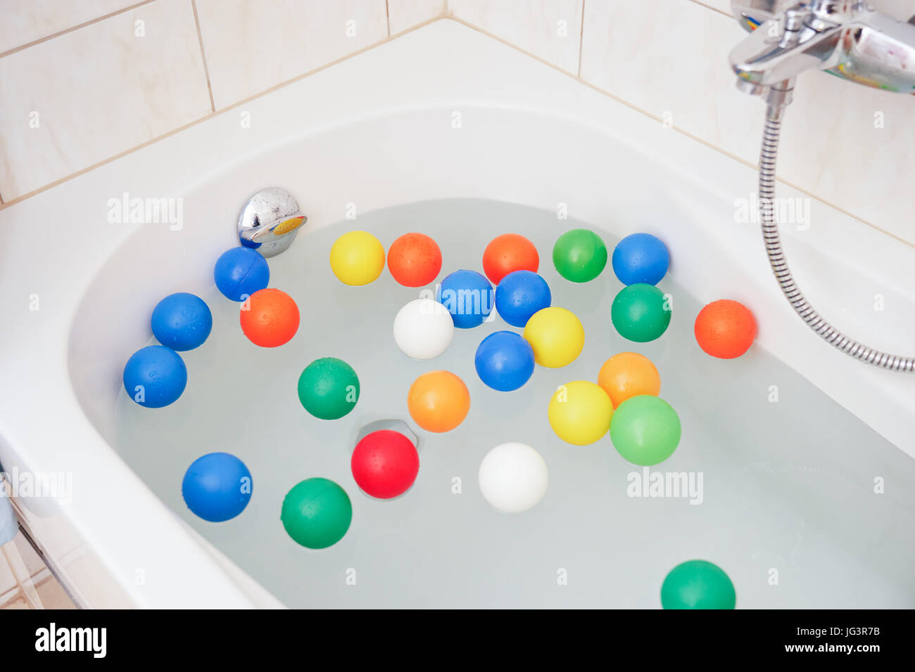 White bathtube with colored plastic balls Stock Photo