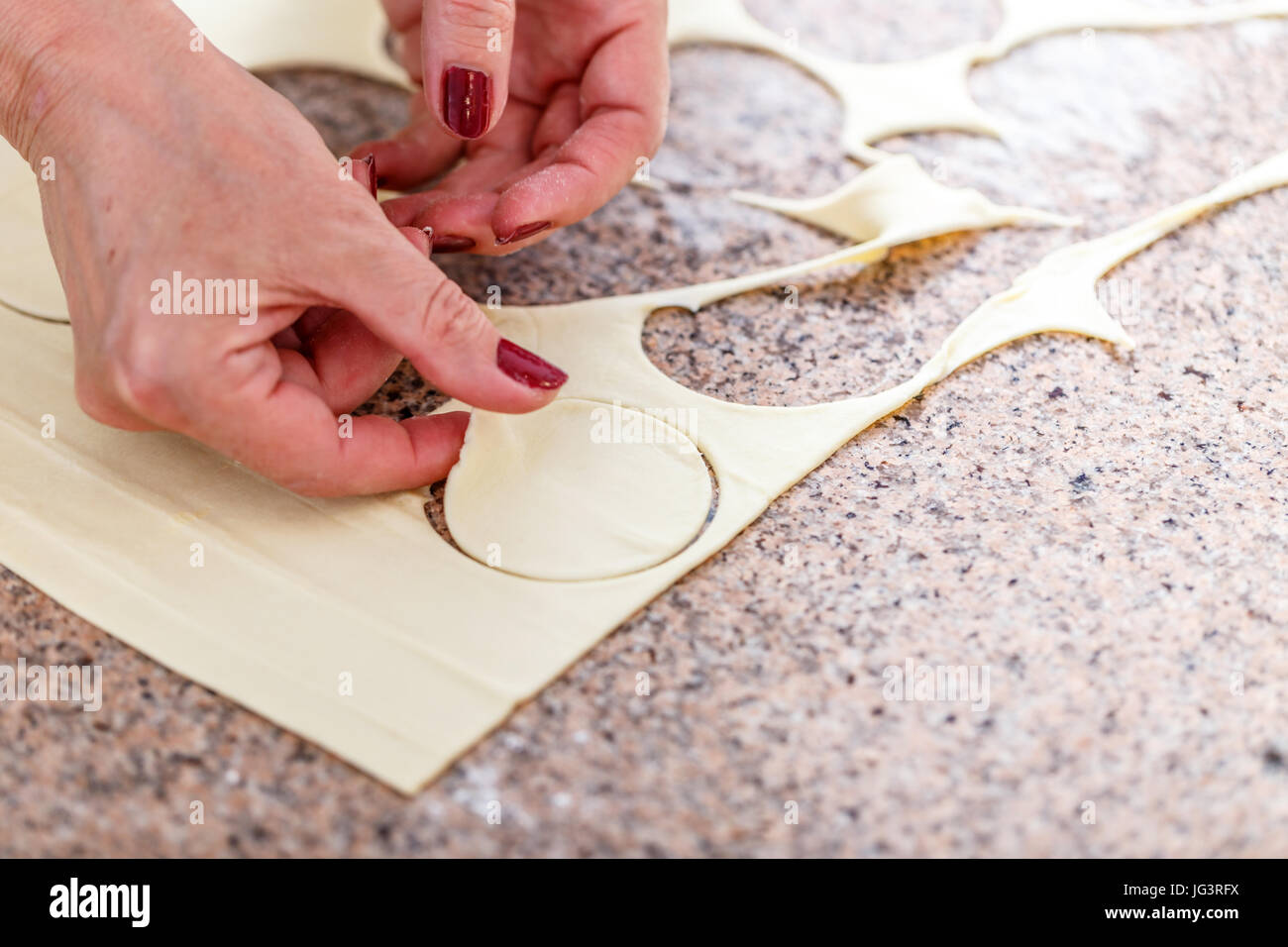 Woman hand cutting out round shaped biscuits from dough Stock Photo