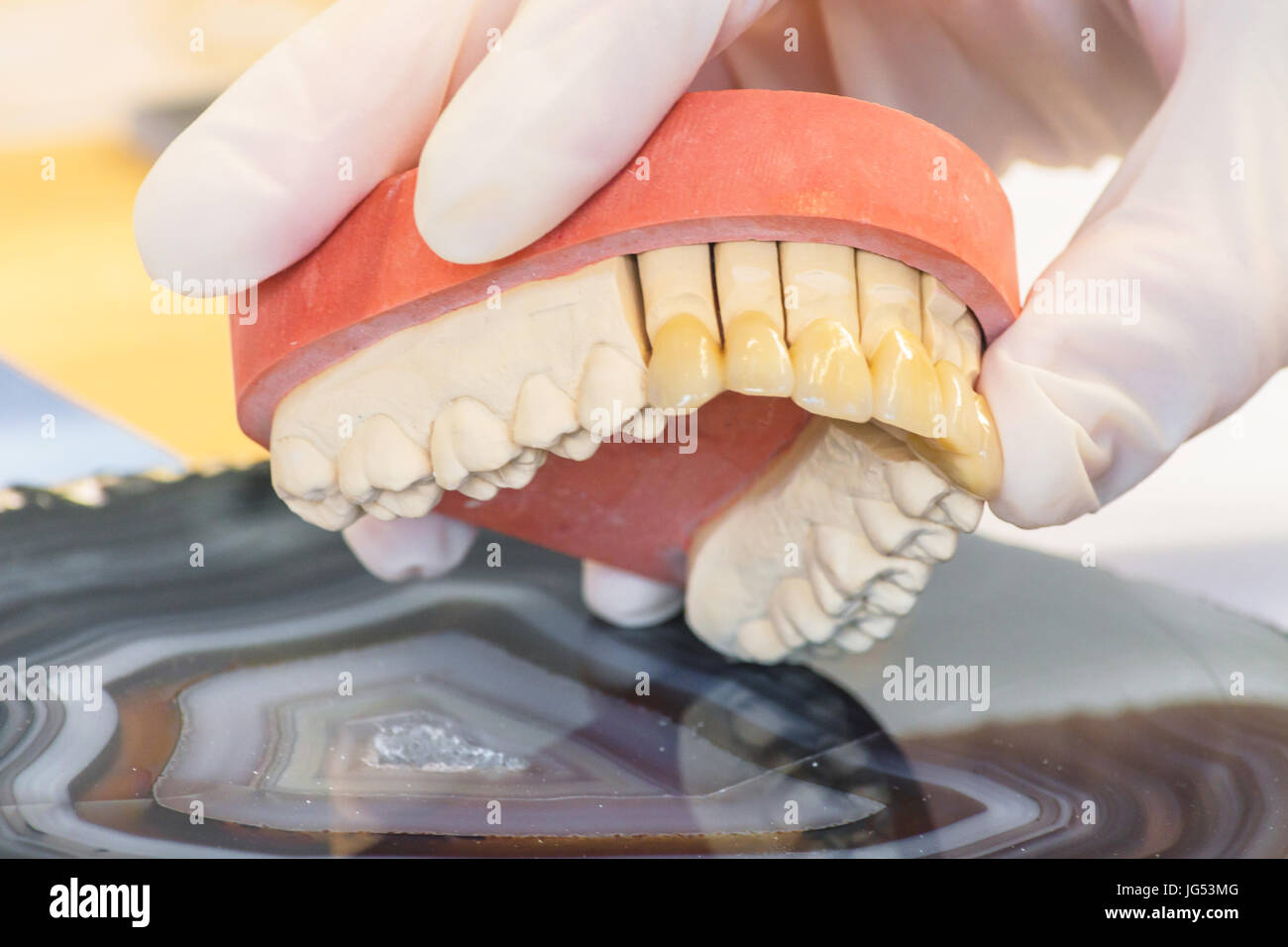 Dentures, prosthesis and oral hygiene. Hands with gloves while working on a dental prosthesis. Stock Photo