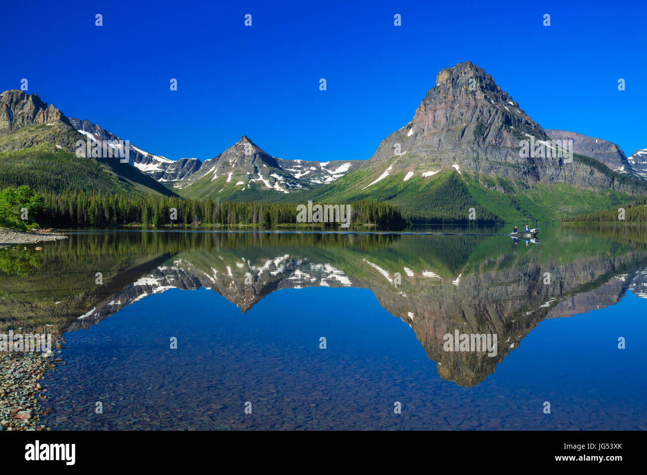 tourists boating across two medicine lake in glacier national park