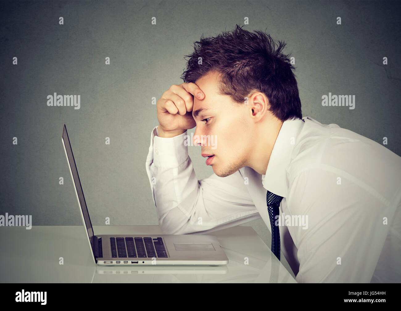 Unhappy stressed sad man sitting at desk in front of his laptop Stock Photo