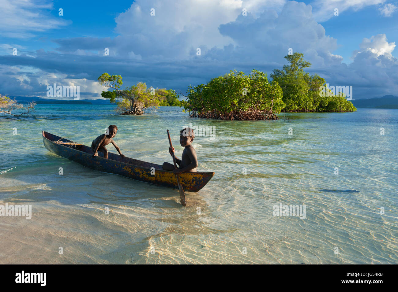 Young boys fishing in the Marovo Lagoon before dramatic clouds, Salomon Islands, Pacific Stock Photo